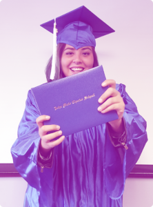 Graduate in cap and gown proudly holds a diploma, celebrating the educational opportunities and student success made possible through the support of community partners.